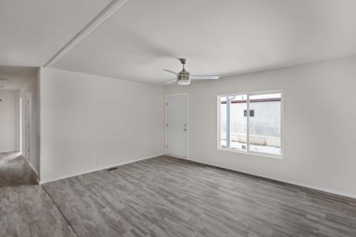 Empty living room with hardwood floors and a ceiling fan.