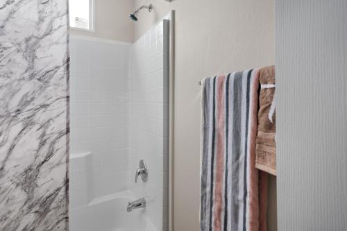 A bathroom with a marble shower wall and towel rack.
