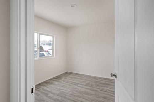 An empty room with white walls and hardwood floors.