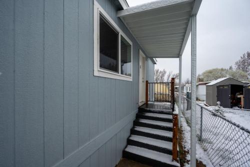 A blue mobile home with snow on the steps.