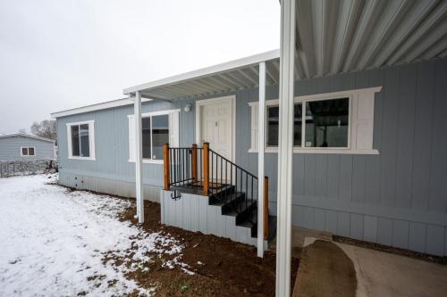 A gray mobile home with snow on the ground.