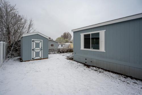 A blue mobile home with snow on the ground.