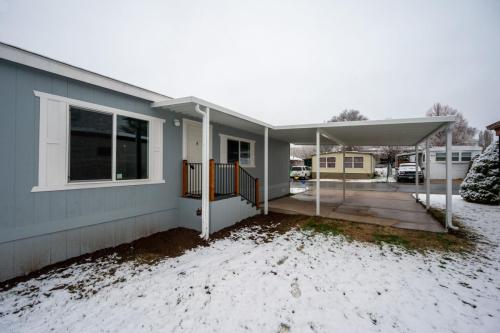 A mobile home in the snow with a covered porch.