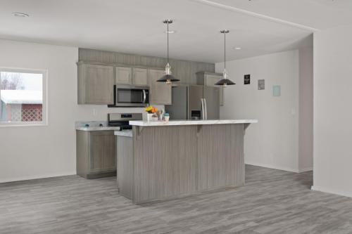 A kitchen with gray cabinets and wood floors.